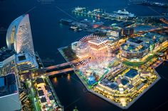 an aerial view of a city at night, with ferris wheel in the foreground