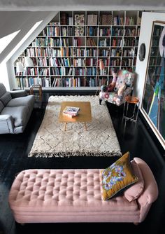 a living room filled with lots of bookshelves next to a couch and coffee table