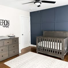 a baby's room with a crib, dressers and a ceiling fan