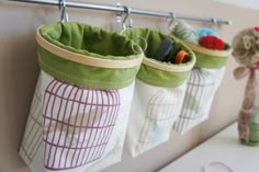 three storage bags are hanging on the wall next to a shelf with a stuffed animal