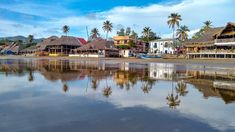 the beach is lined with thatched roofs and palm trees on either side of the water