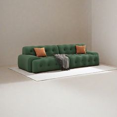 a green couch sitting on top of a white floor in front of a wall with two orange pillows