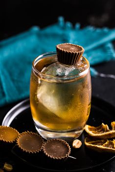 a glass filled with liquid next to some crackers on a black plate and blue towel