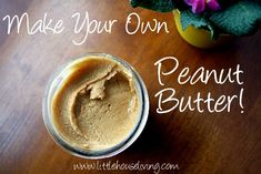 a jar filled with peanut butter sitting on top of a wooden table next to a potted plant