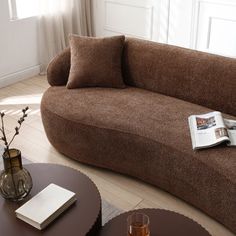 a brown couch sitting on top of a hard wood floor next to a coffee table