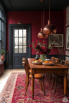 a dining room with red walls and wooden table surrounded by chairs, vases filled with flowers