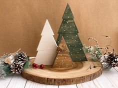 a small wooden christmas tree sitting on top of a piece of wood next to pine cones