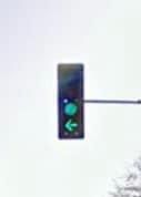 a person flying through the air while holding onto a green traffic light with one hand