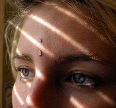 a close up of a person's face with the sun shining through her eyes