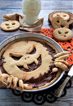 there is a pie with chocolate frosting and pumpkins on the top, next to cookies