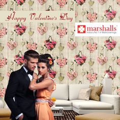 a man and woman standing next to each other in front of a floral wallpaper