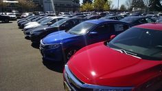 there are many cars parked in the parking lot and one is red, blue, and silver