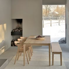 a dining room table with chairs and a bowl of fruit on it in front of an open fire place