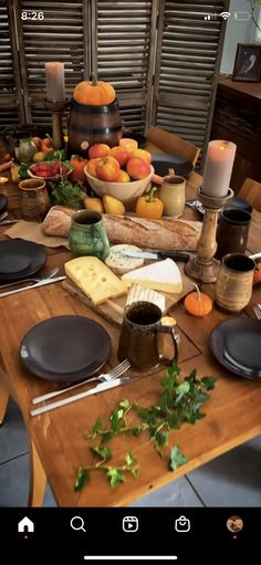 a wooden table topped with lots of plates and bowls filled with food next to candles