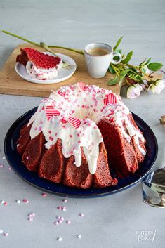 a red velvet bundt cake with white frosting and sprinkles on a blue plate