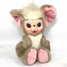 a small stuffed animal with big ears sitting on a white surface