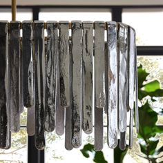 a chandelier hanging from the ceiling in front of a window with trees outside