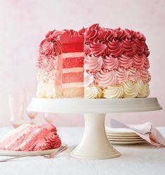 a pink and white cake sitting on top of a plate next to a slice of cake