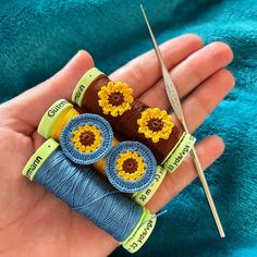 three crocheted sunflowers are sitting on top of yarn and two needles