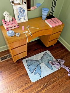 a wooden desk topped with a mirror next to a blue vase and other items on top of a hard wood floor