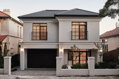 a white two story house with black garage doors