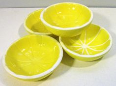 four yellow bowls sitting on top of a white counter