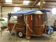 an old camper is parked in a garage with tarp covering it's roof