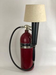 a red fire extinguisher sitting next to a lamp on a white background