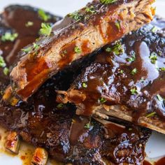 ribs covered in bbq sauce and garnished with parsley on a white plate