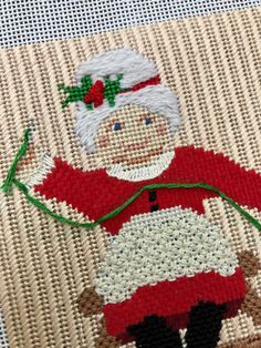 a close up of a piece of cloth with a santa clause on it and a needle