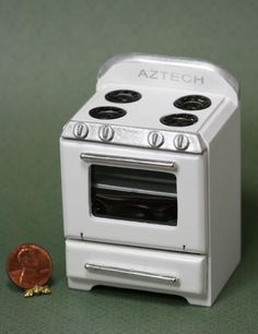 a white stove top oven sitting next to a piece of fruit on a table with a green background