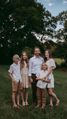 a family posing for a photo in the grass with trees in the background at sunset