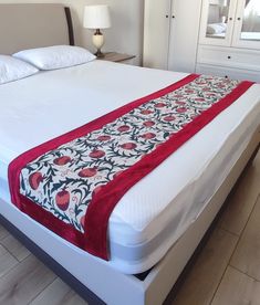 a bed with a red and white bedspread on it's headboard