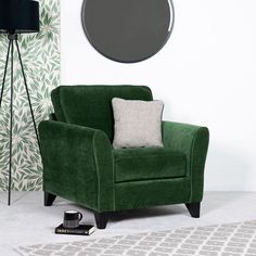 a green chair sitting next to a black lamp and a round mirror on the wall