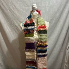 a white mannequin wearing a multicolored knitted scarf with fringes