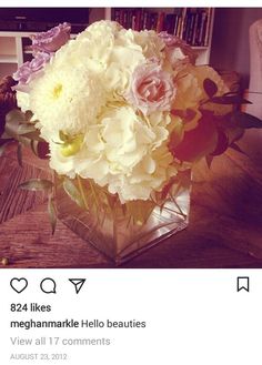 a vase filled with white and pink flowers on top of a wooden table