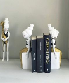 three books are stacked on top of each other in front of two figurines