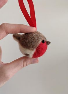 a hand holding a small red and brown bird ornament