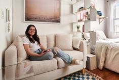 a woman sitting on top of a couch next to a bed