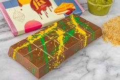 a chocolate bar with yellow and green splatkles next to it on a marble counter