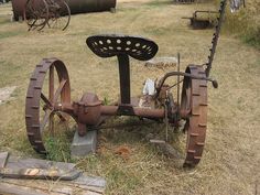 an old rusty machine sitting in the middle of a field next to other metal objects