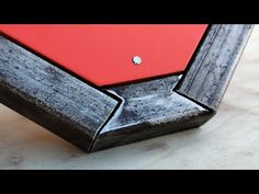 a red and black pool table on a white marble counter top with the bottom section missing