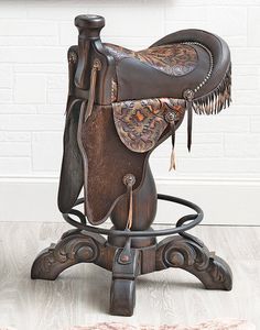 a brown saddle sitting on top of a wooden chair