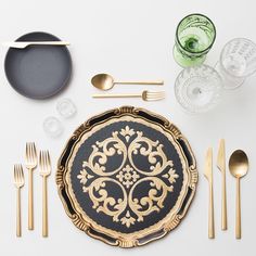 an image of a table setting with gold and black plates, silverware and cutlery