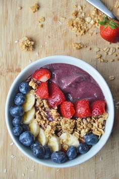 a bowl filled with granola, fruit and yogurt on top of a wooden table