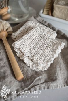 a crocheted dishcloth, brush and soap on top of a cloth covered table