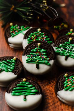 cookies decorated with green and white icing on a table next to a pine tree