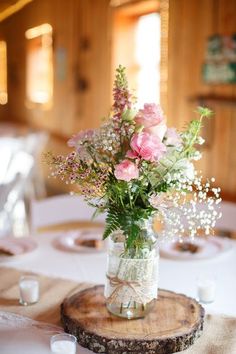 a vase filled with pink flowers sitting on top of a wooden table next to candles