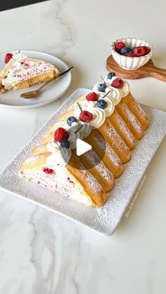 a piece of cake on a plate with berries and whipped cream around the edges, sitting on a marble table