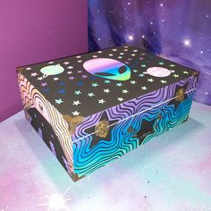 an open box sitting on top of a table next to purple and blue wallpaper